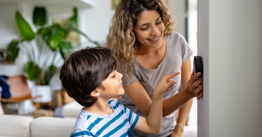 woman and child adjusting thermostat